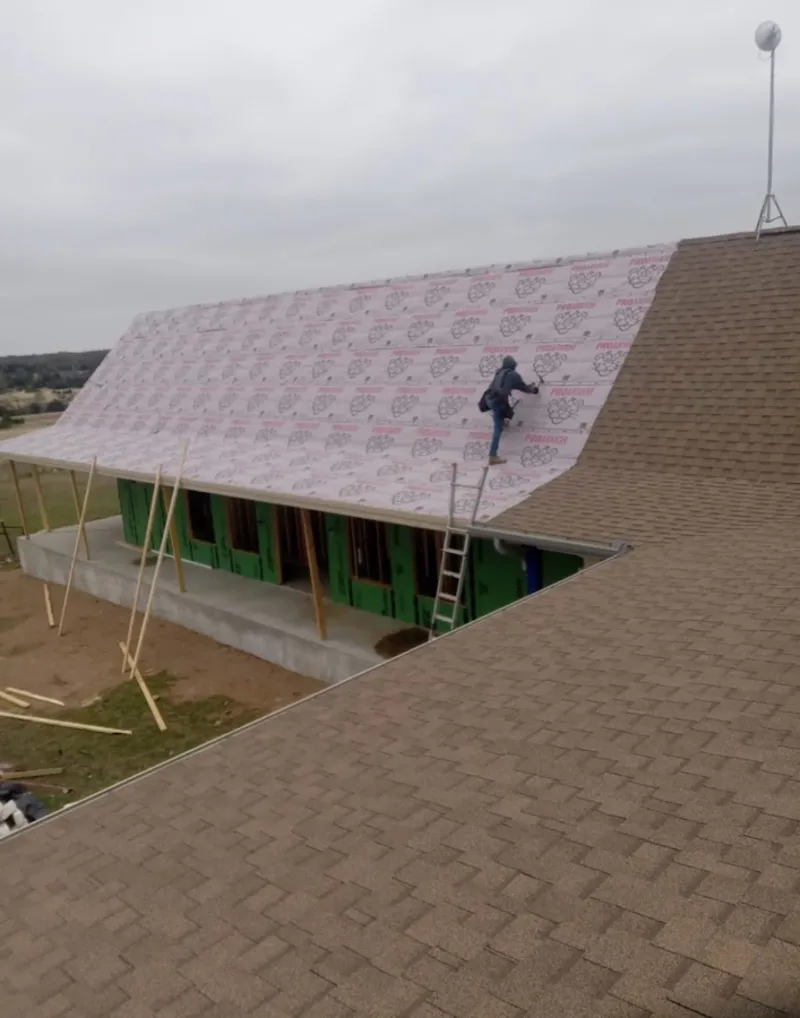 Worker preparing underlayment for a metal roof installation in Fremont